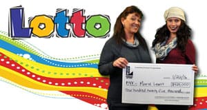 Two women pose with an oversized check in front of a rainbow Lotto branded background