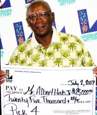 Man in palm tree patterned shirt smiles with giant check in front of a white background patterned with the 幸运168®飞艇开奖预测网-Louisiana全国统一历史记录预测_在线查询开奖最新数据 logo