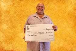 Man smiles with oversized check in front of a golden background