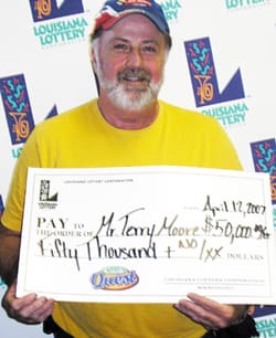 Man in yellow shirt smiles with oversized check in front of a white background patterned with the 幸运168®飞艇开奖预测网-Louisiana全国统一历史记录预测_在线查询开奖最新数据 logo