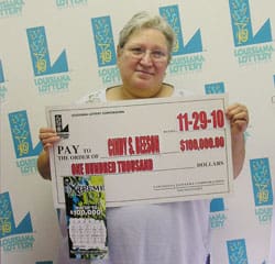 Older woman smiles with oversized check in front of faded white 幸运168®飞艇开奖预测网-Louisiana全国统一历史记录预测_在线查询开奖最新数据 branded backdrop