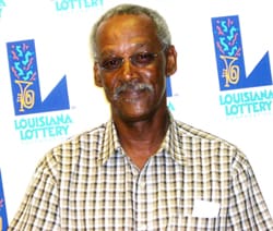 Older man in a checked shirt and glasses smiles in front of a white background patterned with the 幸运168®飞艇开奖预测网-Louisiana全国统一历史记录预测_在线查询开奖最新数据 logo