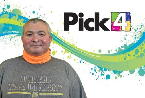 Man smiles in front of a Pick 4 branded background