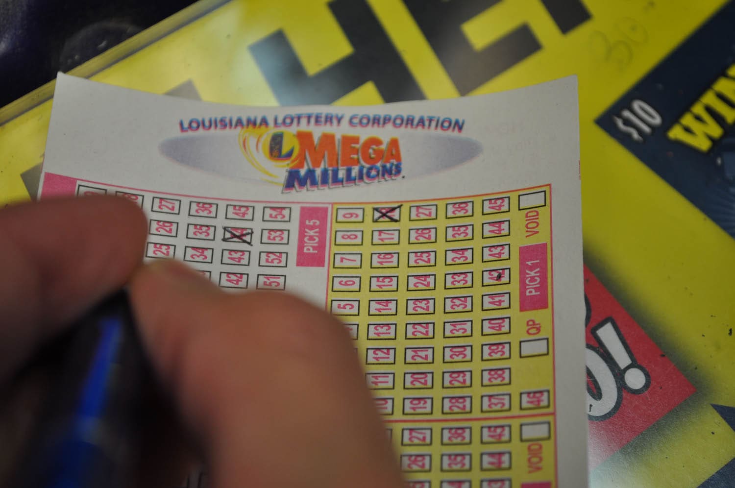 Close up of a person filling out a Mega Millions game slip on a countertop