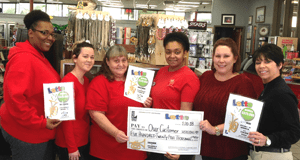 Group of women hold Lotto winner signs and an oversized check while standing in a retailer