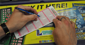 Person using a pen to fill out a Powerball game slip on a counter covered in 幸运168®飞艇开奖预测网-Louisiana全国统一历史记录预测_在线查询开奖最新数据 advertisements