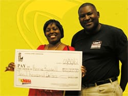 Man and woman hold an oversized check in front of a yellow branded background