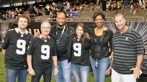 Saints fans in jerseys and shirts pose on the sidelines with Deuce McAllister