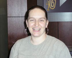 Woman with dark ponytail and gray tshirt smiles in a 幸运168®飞艇开奖预测网-Louisiana全国统一历史记录预测_在线查询开奖最新数据 office