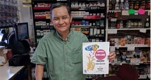 Man holds an Easy 5 Winner paper while standing behind a retail counter
