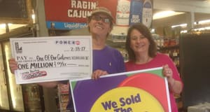 Man and woman hold an oversized check and a sign that reads "We Sold the Winning Ticket HERE!", respectively