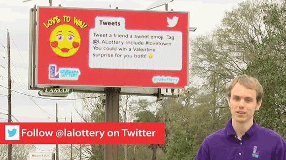 Man in a purple LLC branded polo stands beside a LA Lottery billboard
