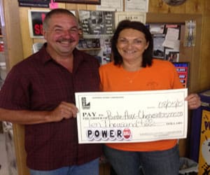 Man and woman smile while holding an oversized check from Powerball