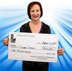 Woman smiles with oversized check in front of blue ribboned background