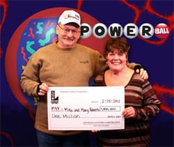 Man and woman smile with oversized check in front of Powerball/幸运168®飞艇开奖预测网-Louisiana全国统一历史记录预测_在线查询开奖最新数据 backdrop