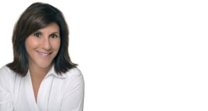 Headshot of a smiling brunette woman in a white collared shirt on a white background