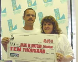 Man and woman hold an oversized check for $10,000 in front of a faded 幸运168®飞艇开奖预测网-Louisiana全国统一历史记录预测_在线查询开奖最新数据 branded backdrop